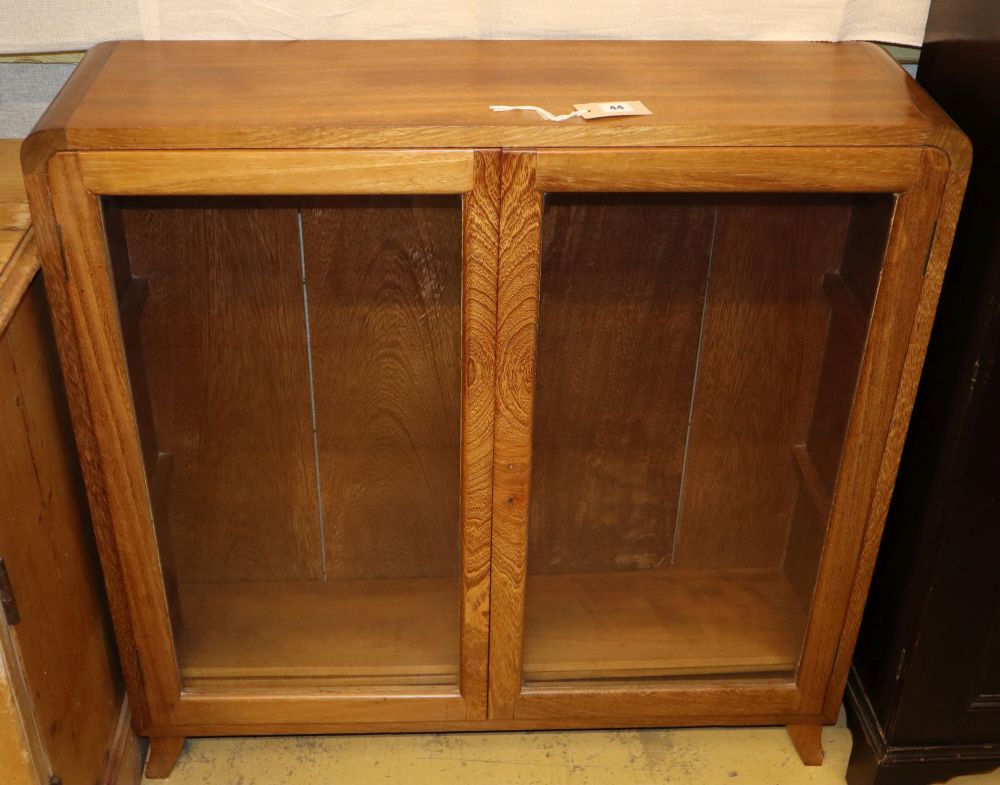 An Art Deco style teak low bookcase fitted a pair of glazed doors, W.90cm, D.25cm, H.92cm